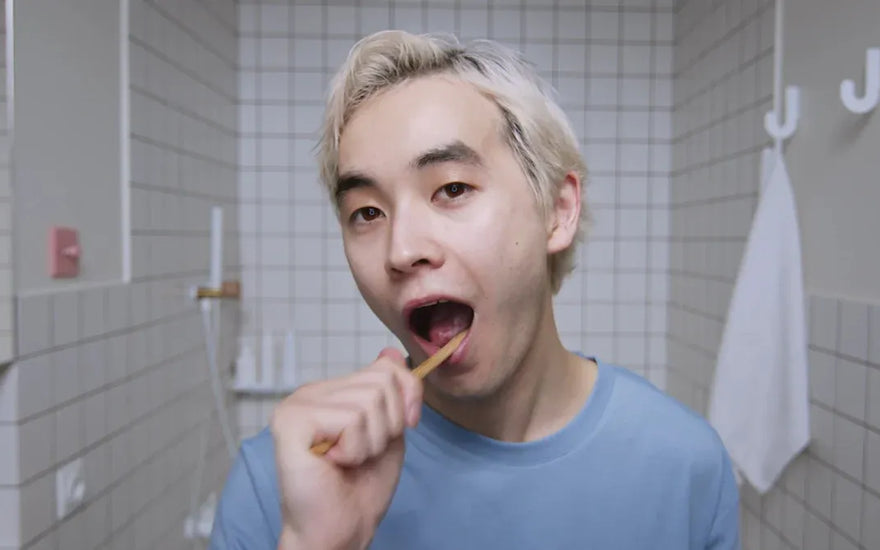 Man brushing his teeth in a tiled bathroom